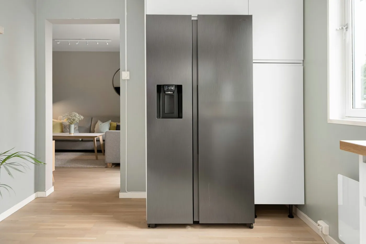 A stainless steel refrigerator standing in a bright, newly finished kitchen.