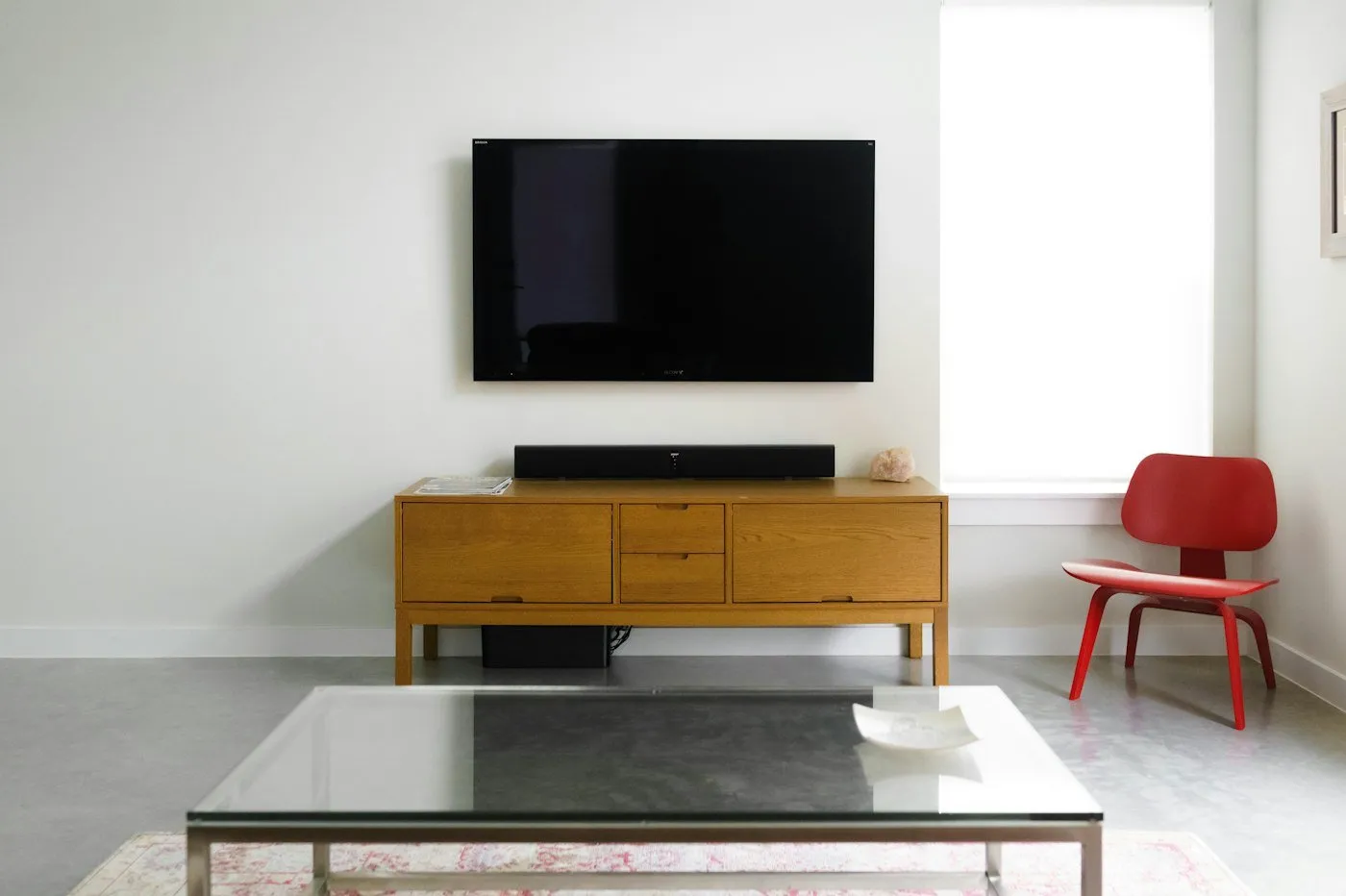 A flat-screen TV mounted on a white wall above a wooden media console.